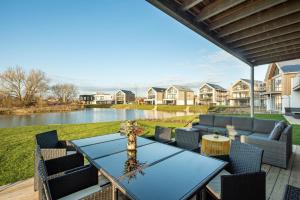 a patio with a table and chairs and a body of water at Minety Lake 72 ML72 Lower Mill Estate Cotswolds in Somerford Keynes