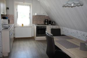eine Küche mit Tisch und Herd und Fenster in der Unterkunft Ferienwohnung Edelweiß im Erzgebirge in Markersbach