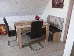 ein Holztisch mit Stühlen und einer Vase mit Blumen darauf in der Unterkunft Ferienwohnung Edelweiß im Erzgebirge in Markersbach + 6 Fotos