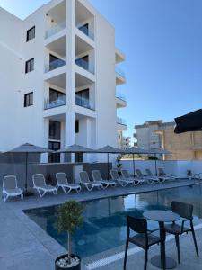 a swimming pool with chairs and a table and a building at Suar Apartment in Ksamil