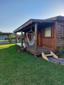 a wooden cabin with a hammock in the grass at La Cabaña de Sofi in Tandil