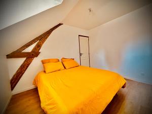 a bedroom with a yellow bed with two pillows at Poule Noire Ukraine in Égreville +24 photos
