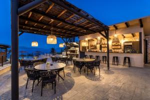 eine Außenterrasse mit Tischen und Stühlen sowie eine Bar in der Unterkunft Ionian Hospitality Resort Suites & Villas in Nikiana
