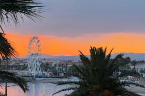 a ferris wheel in a city at sunset at Bleu Azur -Vue Mer 6e Etage - Triangle d'Or in Saint-Raphaël
