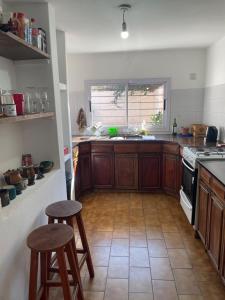una cocina con armarios de madera y 2 taburetes. en Casa de Gregorio, en Córdoba