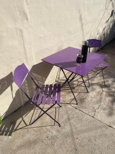 Dos sillas moradas y una mesa morada con un vaso. en Casa de Gregorio, en Córdoba