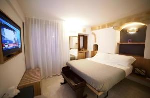 a hotel room with a bed and a television at Casa Festa Rooms in Matera