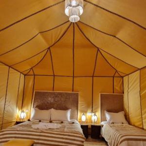 a bedroom with two beds in a tent at Luxury camps merzouga in Merzouga +12 photos
