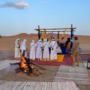 Un grupo de hombres de pie alrededor de un fuego en el desierto. en Luxury camps merzouga, en Merzouga 12 fotos más