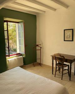 a bedroom with a bed and a desk and a window at Maison Gramme Lussan in Lussan