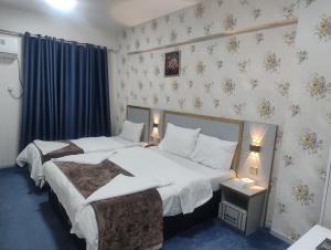 two beds in a hotel room with two lamps at Middle East Hotel Dubai in Dubai