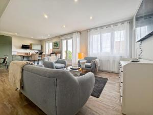 Una sala de estar con un sofá y sillas y una cocina. en L'art de vivre en Baie, bel apt avec parking, en Saint-Valery-sur-Somme