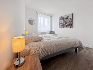 Un dormitorio con una cama y una mesa con una lámpara. en L'art de vivre en Baie, bel apt avec parking, en Saint-Valery-sur-Somme
