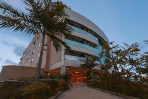 a building with a palm tree in front of it at Verdegreen Hotel in João Pessoa