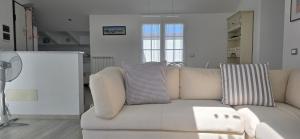 un sofá blanco en una sala de estar blanca en Villa Rocca - mansarda, en Borgio Verezzi