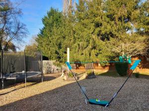 a playground with a swing set and a trampoline at Le Cottage de Maé in Seigy
