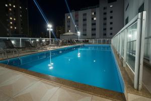 a swimming pool on the roof of a building at night at Apê super charmoso! Ar-condicionado e piscina in Brasilia