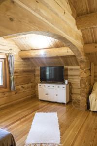 a living room with a tv and a room with wooden walls at A fák ölelése vendégház in Bükkaranyos