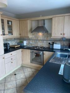 a kitchen with wooden cabinets and a stove and a sink at Portstewart Escape in Portstewart