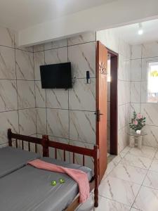 a bedroom with a bed and a tv on a wall at Paraíso dos pássaros in Búzios