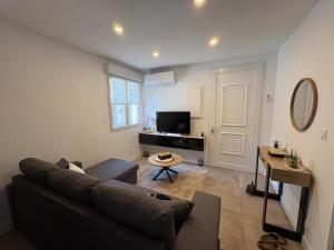 a living room with a couch and a tv at Chez Isa, Les pieds dans l'eau in Valras-Plage