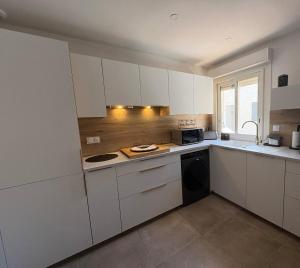 a kitchen with white cabinets and a stove top oven at Chez Isa, Les pieds dans l'eau in Valras-Plage