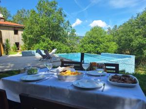 a table with a plate of food and wine glasses at Casa com piscina privada e jacuzzi no Gerês in Pandoses