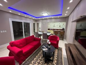 ein Wohnzimmer mit einem roten Sofa und einem Tisch in der Unterkunft Casa de Alto Padrão Verdes Campos POA in Porto Alegre