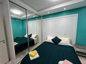 ein Schlafzimmer mit zwei Betten und einem Spiegel in der Unterkunft Casa de Alto Padrão Verdes Campos POA in Porto Alegre