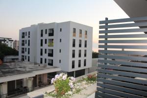 a white apartment building with flowers on the balcony at AMD - garsonjera 312 in Dobra Voda