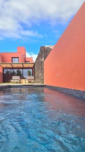 a house with a swimming pool next to a red building at Villa São Roque in Ponta Delgada