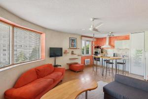 ein Wohnzimmer mit einem orangenen Sofa und einer Küche in der Unterkunft Charmant Appartement T2 - Garage in Villeurbanne