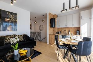 a living room and kitchen with a table and a couch at Apartament Ustka Holiday - Black Alice z balkonem i klimatyzacją in Ustka