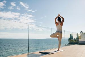 a woman doing yoga on a balcony overlooking the ocean at Hotel Istra - Liburnia in Opatija