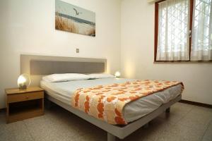 a bedroom with a bed and a table and a window at Villa Capinera in Lignano Sabbiadoro