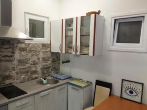 a kitchen with white cabinets and a sink and a table at Apartment Marci in Donji Morinj +14 photos
