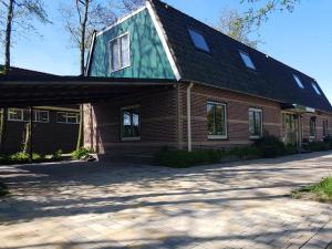 een huis met een groen dak en een oprit bij Appartement De Molshoop II in Landsmeer