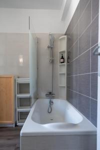 a white bath tub in a bathroom with gray tiles at Le Victoire - Escale cosy à Toulon centre in Toulon +18 photos
