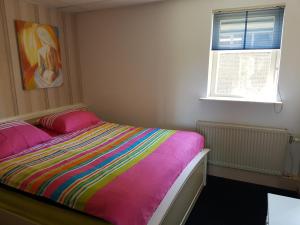 a bedroom with a bed with a colorful blanket at Appartement De Molshoop II in Landsmeer