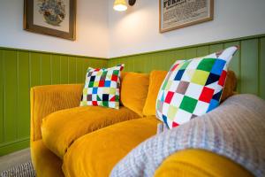 a yellow couch with colorful pillows in a living room at 4 Low Rake - Former Miners Cottage in Glenridding +13 photos