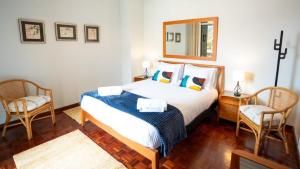 a bedroom with a bed with two chairs and a mirror at Starry View in Funchal