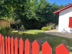 a red picket fence in a yard with a bench at charmante maisonnette tout confort avec sauna in Bidache +9 photos