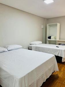 two beds in a room with white sheets at Hotel e Restaurante Casa Velha in Barra Longa