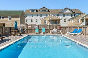 una piscina con sillas, una mesa y un patio en Seawalk Condos, en Kill Devil Hills