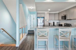 Una cocina con gabinetes blancos y una encimera con taburetes. en Seawalk Condos, en Kill Devil Hills