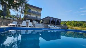 a swimming pool with chairs and a house at Vila Monti 