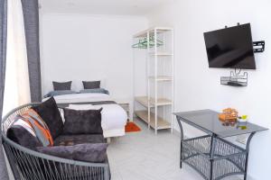 a living room with a bed and a couch and a tv at Wild Wood Cottages, Naivasha in Naivasha