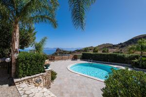 een zwembad in een tuin met een palmboom bij Villa Torre del Mare in Scopello