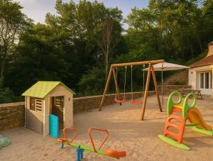 une aire de jeux avec deux balançoires et une structure de jeu dans l'établissement Gîte Le Vélo Rouge - Airco & Parking, à Sarlat-la-Canéda