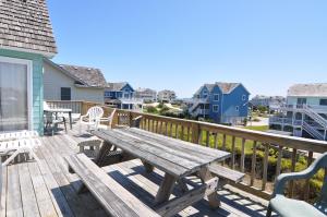 eine Holzterrasse mit einem hölzernen Picknicktisch und Stühlen in der Unterkunft Seaside 58 by Village Realty in Nags Head